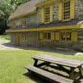 Edificio histórico con ventanas amarillas y mesas de picnic al aire libre