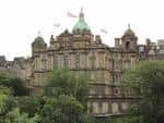 Vista exterior del edificio principal de Bank of Scotland en Edimburgo con cúpula verde y banderas