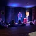 Escenario del club con un comediante en acción y público sentado