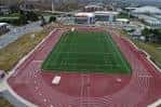 Plano cenital del estadio mostrando la pista roja y el césped verde en buen estado