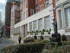 Vista exterior del edificio con estatua y jardines frontales