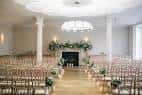 Sala de ceremonias interior decorada para boda con sillas y arcos florales
