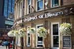 Fachada exterior del pub The Head of Steam con macetas colgantes
