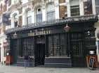 Fachada del pub The Castle en Londres con letrero negro y ventanas grandes