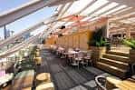 Interior del techo de Circe's Rooftop con mesas y sillas bajo una estructura de madera