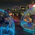 Burbujas iluminadas en el techo de Circe's Rooftop con vistas al London Eye por la noche