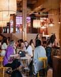 Área social interior con personas reunidas en mesas, mostrando el ambiente del lugar