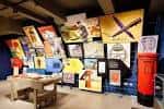 Exposición interior con carteles históricos y caseta de correo roja