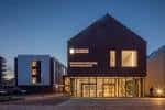 Fachada principal del hotel durante la noche con iluminación cálida en entradas y ventanales