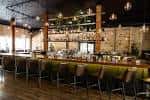 Vista del bar interior de Varley con estanterías de botellas y asientos en la barra