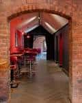 Interior del bar con arcos de ladrillo y mesas rojas