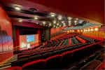 Interior del auditorio con butacas rojas y escenario iluminado