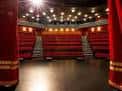Escenario principal con cortinas rojas abiertas y luces de techo