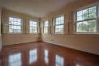 Habitación vacía con suelo de madera pulida y grandes ventanas