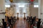 Sala preparada para una boda con sillas negras y fondo decorativo brillante