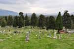 Paisaje del cementerio con filas de tumbas y montañas al fondo