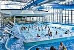 Zona de piscina recreativa con tobogán y personas disfrutando