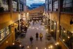 Vista interior del patio central de The Stutz con iluminación cálida y personas caminando