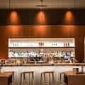 Interior del bar del hotel con iluminación cálida y estantería de botellas