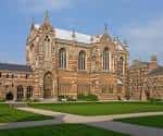 Vista exterior de la capilla de Keble College en Oxford con arquitectura gótica y césped frente a ella