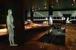 Interior del museo con réplicas de figuras romanas y vistas a través de ventanas hacia los restos arqueológicos