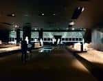 Interior amplio del centro de interpretación con iluminación tenue y exposición de los restos históricos