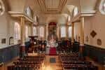 Interior de la iglesia mostrando las bancas, el altar y la arquitectura clásica del espacio