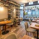 Interior del restaurante con mesas y estanterías de botellas
