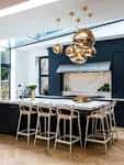 Cocía contemporánea con encimera blanca y lámparas doradas colgantes