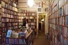 Interior de la librería con estanterías llenas de libros y una persona en el fondo