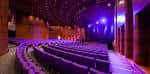 Interior de un auditorio con butacas y escenario iluminado