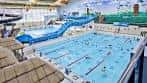 Piscina olímpica cubierta con carriles marcados y tobogán azul en el fondo
