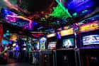 Interior del NQ64 Arcade Bar con máquinas retro y luces de neón