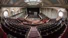 Interior del auditorio con butacas rojas dispuestas en gradas y escenario