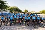 Grupo de ciclistas posando frente al circuito en uniforme azul, mostrando la actividad deportiva del lugar