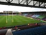 Campo de juego del Twickenham Stoop con postes de rugby y asientos vacíos bajo la estructura del techo