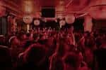 Vista general del salón de eventos con público animado y decoración en tonos rojos