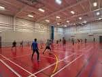 Pista deportiva interior para bádminton con jugadores en acción