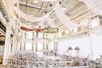 Decoración de boda con telas colgantes blancas y sillas dispuestas para ceremonia
