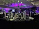 Sala de eventos decorada con mesas redondas y luces púrpuras para recepción o cena