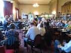Interior del club mostrando sala social con personas reunidas en mesas y ambiente acogedor