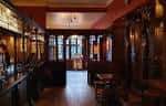 Interior del pub con barra de madera y mesas dispuestas para clientes