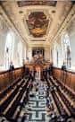 Interior de la capilla del Trinity College con bancos de madera y techo decorado