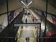 Interior de la estación mostrando escaleras mecánicas y pasarela con iluminación moderna