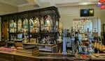 Barra principal del pub con estanterías de botellas y ambiente tradicional