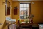 Interior de una habitación amarilla con ventana y decoración histórica