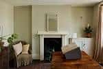 Sala de estar con chimenea, espejo y mobiliario antiguo