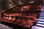 Interior de la sala de cine con butacas reclinables y escalera iluminada