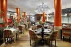 Sala de comedor o lounge con mesas, sillas tapizadas y columnas naranjas