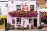 Fachada rosa de un local comercial con flores y decoración festiva